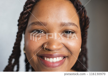 Young biracial woman with braided hair is smiling at camera in a modern business office Young biracial woman with braided hair is smiling at camera in a modern business office 116130970