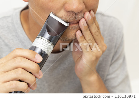A man shaving his beard on a white background A man shaving his beard on a white background 116130971