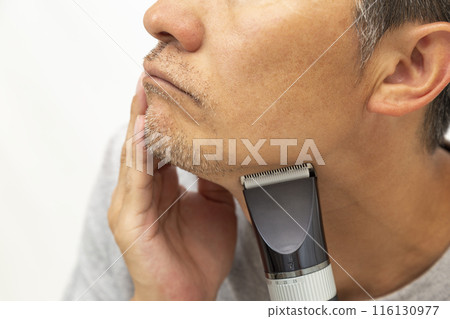A man shaving his beard on a white background 116130977
