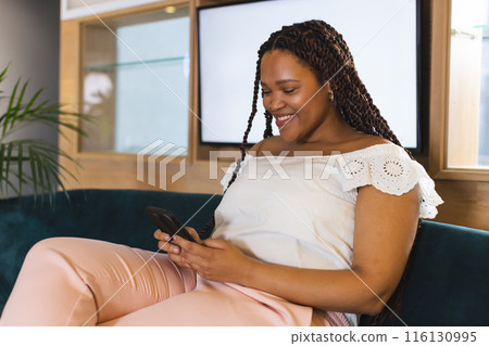 Biracial woman with braided hair using smartphone in a modern business office Biracial woman with braided hair using smartphone in a modern business office 116130995