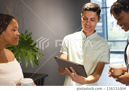 A diverse group of colleagues looking at a tablet in a modern business office 116131004