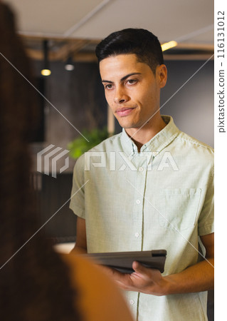 A biracial man holding tablet, talking to someone off-camera in a modern business office A biracial man holding tablet, talking to someone off-camera in a modern business office 116131012