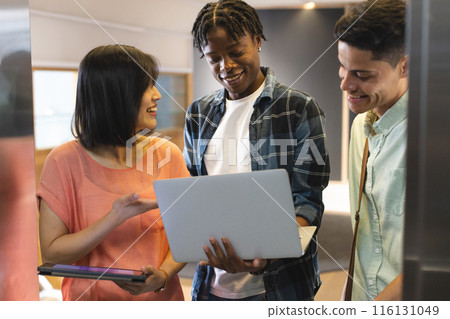 Diverse group of colleagues sharing content on a laptop in a modern business office 116131049