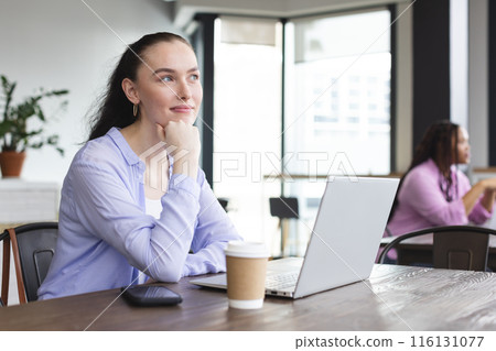 Biracial woman with laptop looking thoughtful at cafe 116131077