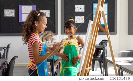 In school, in art class, a diverse group of young girls are painting 116131429