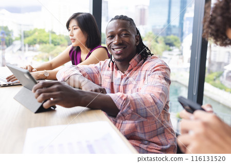 Diverse group of young adults working together in a modern business office, smiling at camera Diverse group of young adults working together in a modern business office, smiling at camera 116131520