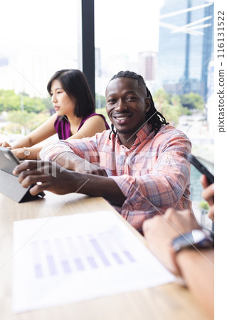 Asian woman and African American man sitting in a modern business office, looking at charts 116131522