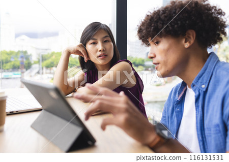 Diverse colleagues looking at tablet in cafe 116131531