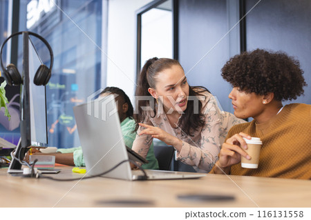 Diverse colleagues discussing over computer in office 116131558