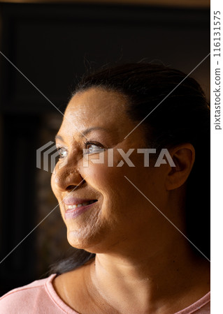 Mature biracial woman looking away, wearing pink top at home Mature biracial woman looking away, wearing pink top at home 116131575