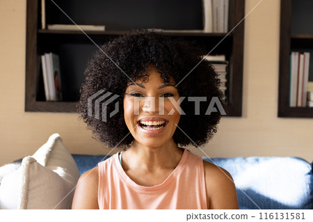 Young biracial woman with curly black hair smiling at home 116131581