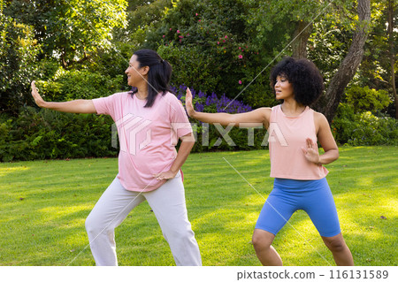 Biracial mother and daughter practicing yoga in garden at home Biracial mother and daughter practicing yoga in garden at home 116131589