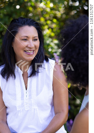 A mature biracial woman is talking to her young daughter in the garden at home 116131707