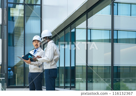 A group of multinational engineers having a conversation in front of a building 116132367