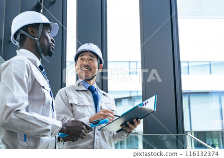 Group of multinational engineers having a conversation in a building 116132374
