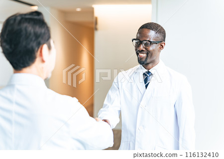 Multinational group in white coats shaking hands in lobby 116132410