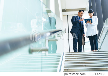 A group of businessmen and engineers in white coats talking in the lobby 116132436