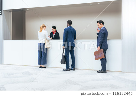 Multinational people checking in at a hotel front desk Multinational people checking in at a hotel front desk 116132445