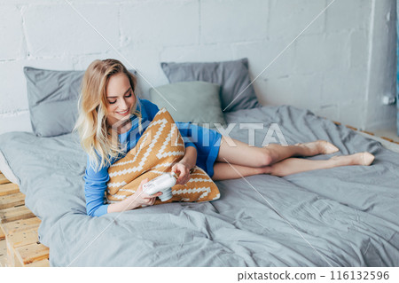 girl hugging the pillow and looking at the photos from the digital camera girl hugging the pillow and looking at the photos from the digital camera 116132596