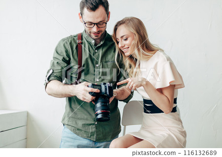 a pleasant photographer showing models the photos on his camera 116132689