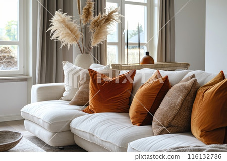 Stylish interior design with a white sofa adorned by orange cushions and sophisticated decor 116132786