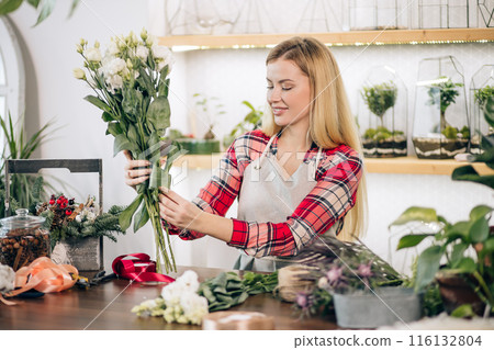 woman florist composing bouquet, enjoy working with flowers 116132804