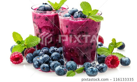 Two glasses of vibrant blueberry smoothies adorned with fresh mint leaves and surrounded by scattered berries 116133335