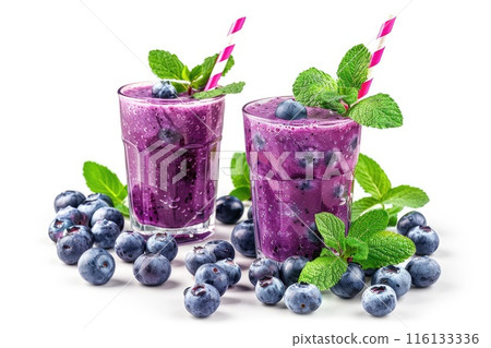 Two glasses of vibrant blueberry smoothies adorned with fresh mint leaves and surrounded by scattered berries 116133336