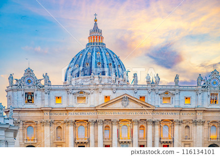 A scenic view of the iconic dome of St. Peters Basilica in Vatican City at sunset. The buildings facade and dome are illuminated by the warm glow of the evening light. 116134101