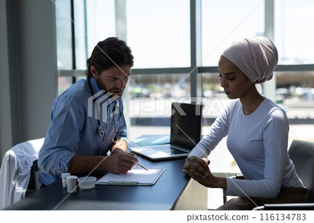 Disabled Biracial woman and Caucasian male doctor interacting with each other 116134783