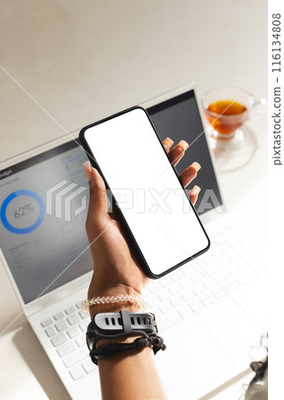 A young African American female professional holding up a smartphone at home with copy space A young African American female professional holding up a smartphone at home with copy space 116134808