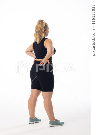 Caucasian young female plus size model on white background wearing black sportswear, looking away Caucasian young female plus size model on white background wearing black sportswear, looking away 116135035
