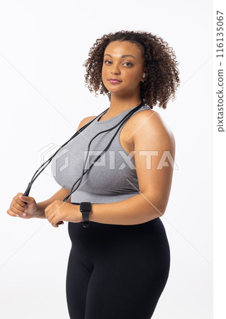 A biracial young female plus size model holding a jump rope on a white background 116135067