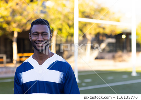 African American young male athlete standing on a football field, wearing a jersey, copy space 116135776