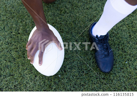 African American young male athlete model holding rugby ball on field outdoors on grass African American young male athlete model holding rugby ball on field outdoors on grass 116135815