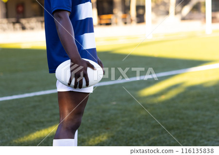 African American young male athlete holding rugby ball, wearing blue and white, copy space 116135838