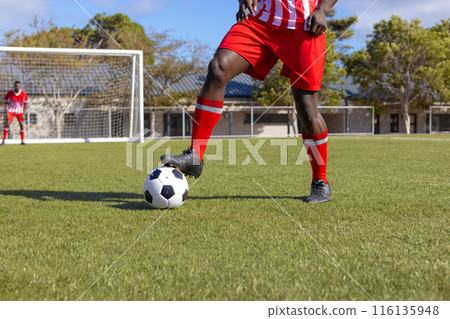 Two African American young male athletes are playing soccer on field outdoors 116135948