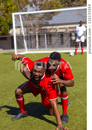 Three African American young male athletes are celebrating on a soccer field outdoors Three African American young male athletes are celebrating on a soccer field outdoors 116135954