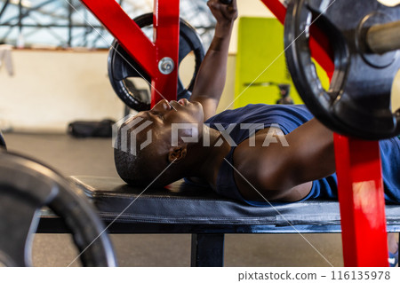 African American young male athlete in gym lifting weights, focusing on exercise 116135978