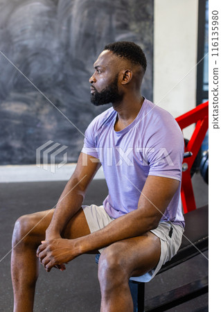 African American young male athlete sitting on a bench in a gym, resting, copy space 116135980