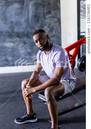 African American young male athlete sitting on a bench in a gym, copy space African American young male athlete sitting on a bench in a gym, copy space 116136001