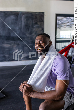 African American young male athlete resting in gym, towel around neck, copy space 116136008