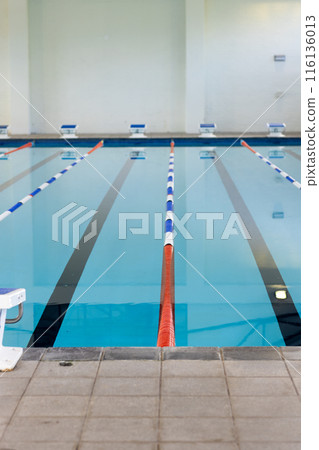 Empty swimming pool lanes indoors await swimmers, marked by colorful lane dividers, copy space Empty swimming pool lanes indoors await swimmers, marked by colorful lane dividers, copy space 116136013