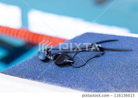 Swimming goggles resting on edge of indoor pool, close-up view, copy space Swimming goggles resting on edge of indoor pool, close-up view, copy space 116136015