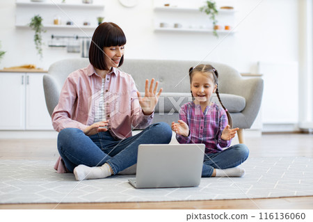 Mother and daughter having online video call at home together 116136060