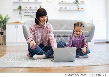 Mother and daughter using laptop on living room floor together Mother and daughter using laptop on living room floor together 116136121