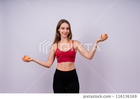 Happy cheerful young blond woman holding nectarines in hands over chest 116136169