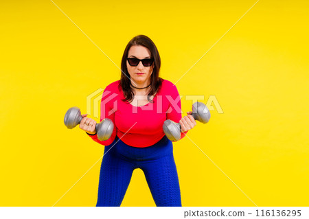 Sporty model with curvy figure with dumbbells. Dynamic movement. Motivation and healthy lifestyle Sporty model with curvy figure with dumbbells. Dynamic movement. Motivation and healthy lifestyle 116136295