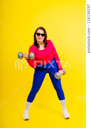 Sporty model with curvy figure with dumbbells. Dynamic movement. Motivation and healthy lifestyle Sporty model with curvy figure with dumbbells. Dynamic movement. Motivation and healthy lifestyle 116136297