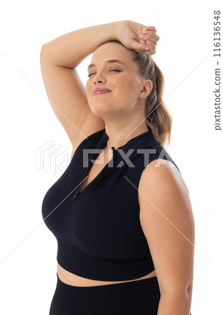 Plus size Caucasian female model stretches arm behind head on white background Plus size Caucasian female model stretches arm behind head on white background 116136548